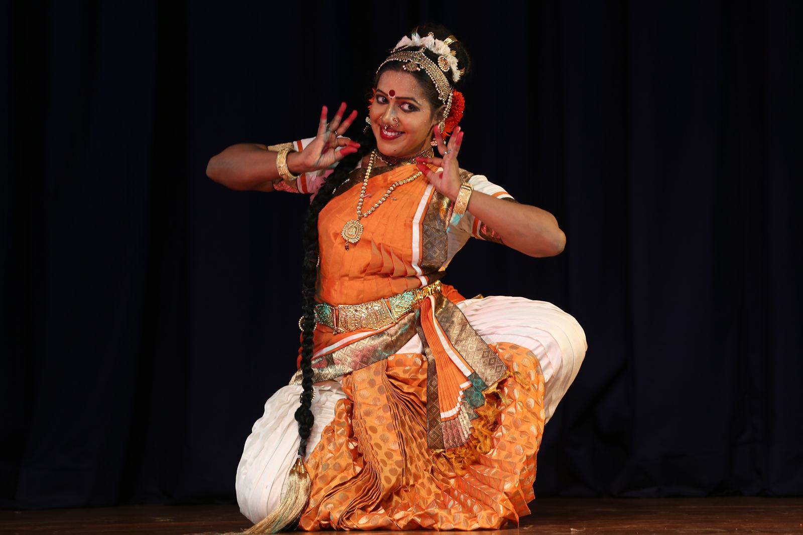 Guru and students holding a namaste posture on stage