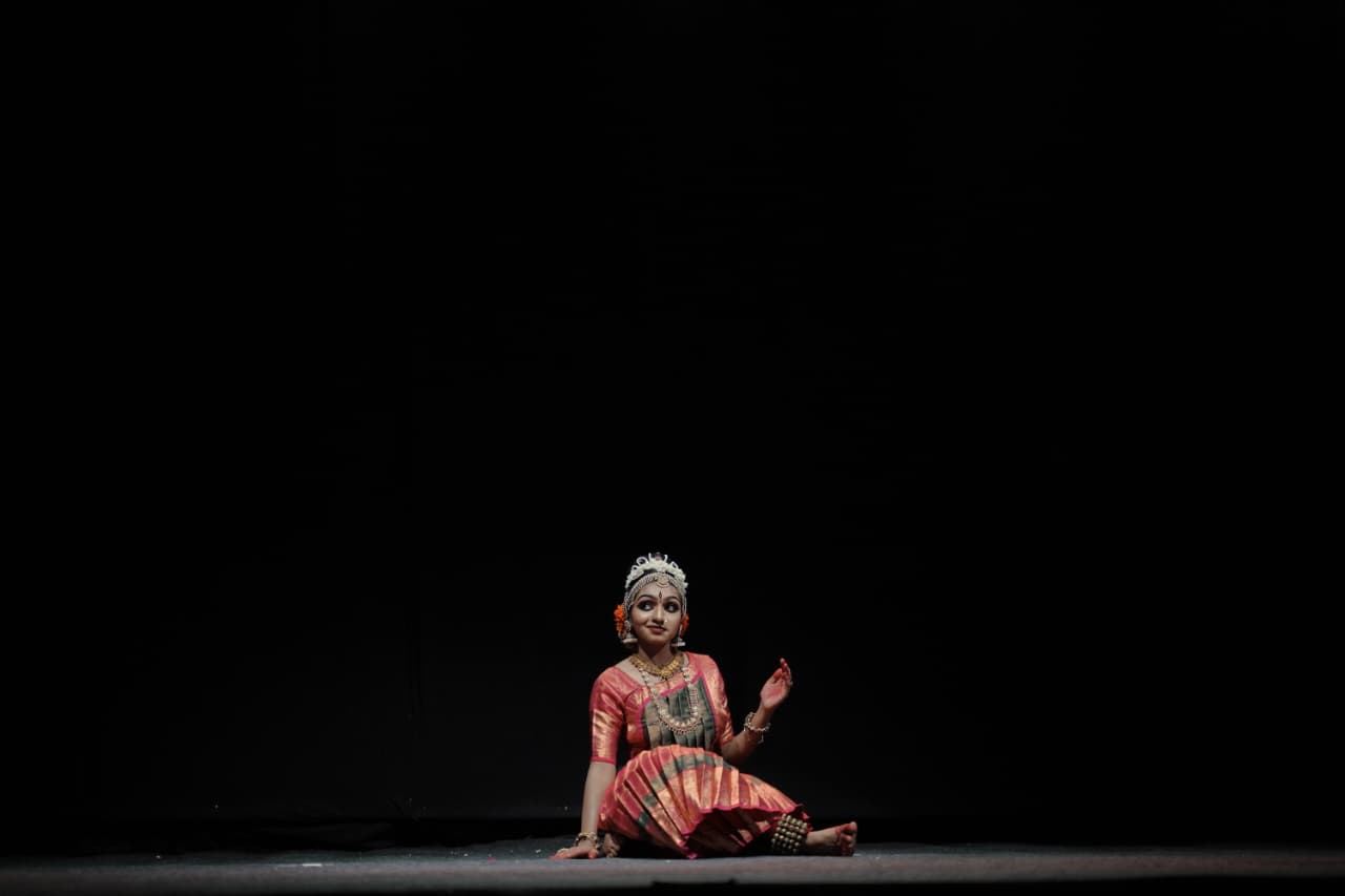 Solo classical dancer seated in a quiet stage moment